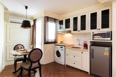 a kitchen with white cabinets and a table and chairs at The LA49 Hotel in Bangkok