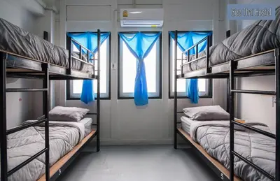 two bunk beds in a room with blue curtains at Zee Thai Hostel in Bangkok