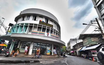 a building on a street with people sitting in front of it at Zee Thai Hostel in Bangkok