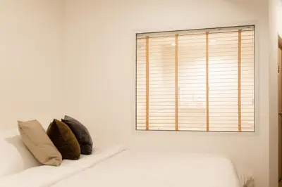 a white couch with two pillows on it next to a window at Hotel PaPa Bangkok Siriraj in Bangkok