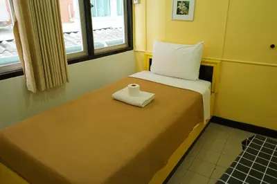 a small room with a bed with a napkin on it at Yes Kaosan in Bangkok
