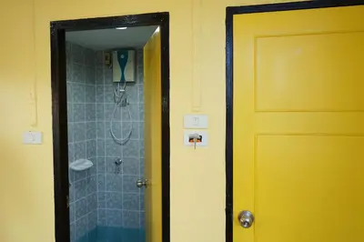 a bathroom with a shower and a yellow door at Yes Kaosan in Bangkok