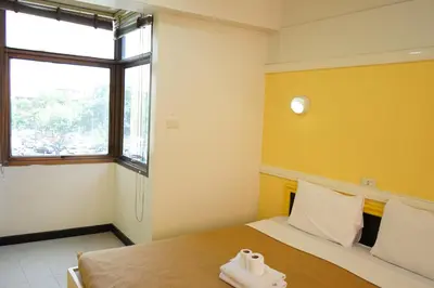 a small room with a bed with a window at Yes Kaosan in Bangkok