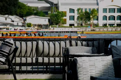 a group of benches next to the water with boats at Theatre Residence in Bangkok