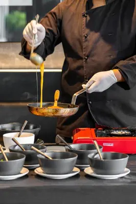 a chef is preparing food in a frying pan at Theatre Residence in Bangkok