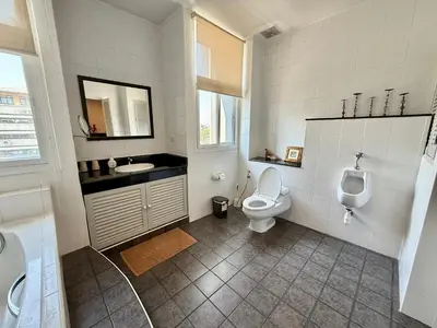 a bathroom with a toilet and a sink and a urinal at Samsen Suites Spacious 2BR Contemporary Thai Style in Bangkok