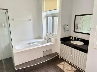 a bathroom with a tub and a sink and a window at Samsen Suites Spacious 2BR Contemporary Thai Style in Bangkok