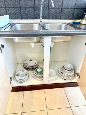 a kitchen sink with plates and dishes under it at Samsen Suites Spacious 2BR Contemporary Thai Style in Bangkok