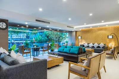 a living room with couches and chairs and a clock at Livotel Hotel Hua Mak Bangkok in Bangkok