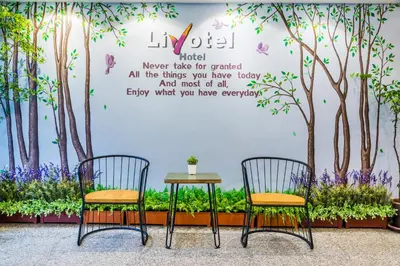 a table and two chairs in front of a wall with trees at Livotel Hotel Hua Mak Bangkok in Bangkok