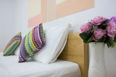 a bed with two pillows and a vase of flowers at Jr Mansion On Nut Soi 25 in Bangkok