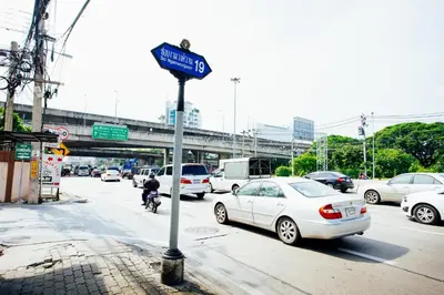 a street sign on the side of a road with cars at Grand Residence Ngamwongwan 19 in Nonthaburi