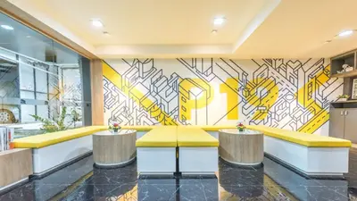 a lobby with yellow benches and a mural at Collection O Pratunam 19 Hotel in Bangkok