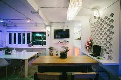a dining room with a wooden table and a tv at Diff Hostel in Bangkok