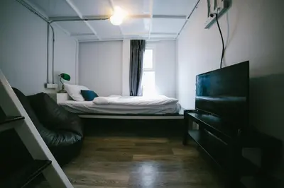 a small room with a bed and a window at Diff Hostel in Bangkok