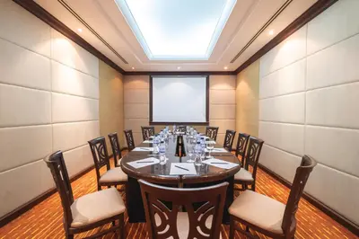 a room with a long table with chairs and a projection screen at Zenith Sukhumvit Hotel, Bangkok in Bangkok