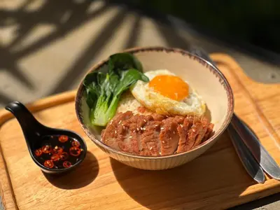 a bowl of food with an egg on a wooden tray at Anna-Nava Pakkret Hotel in Nonthaburi