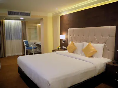 a hotel room with a large white bed with yellow pillows at Kingston Suites Bangkok in Bangkok
