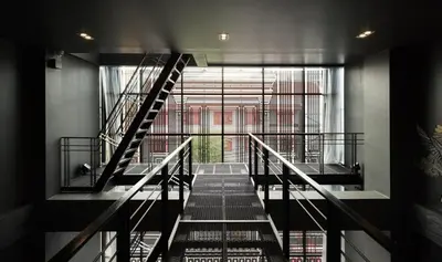 a staircase in a building with a large window at Issara by D Hostel in Bangkok