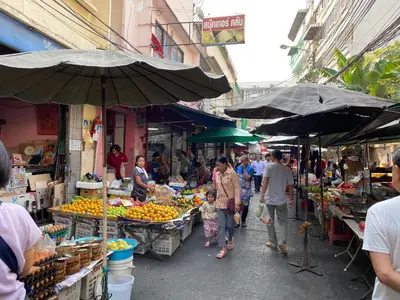 a group of people walking through an outdoor market at Issara by D Hostel in Bangkok