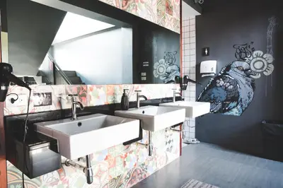 a bathroom with three sinks and a bird painted on the wall at Issara by D Hostel in Bangkok