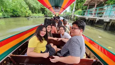 a group of people riding in a boat on a river at Issara by D Hostel in Bangkok