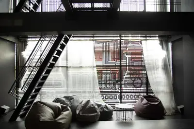 a room with a window with a ladder and a couch at Issara by D Hostel in Bangkok