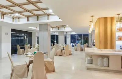 a dining room with white chairs and tables in a building at Sunday Platinum Suites in Bangkok