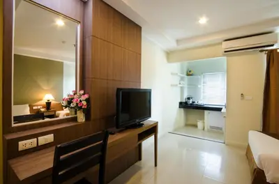 a living room with a television on a wooden wall at Sunday Platinum Suites in Bangkok