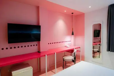 a pink room with a desk and a tv at Budacco The Living Place in Bangkok