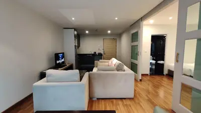 a living room with two white couches and a television at The Bless Hotel and Residence in Bangkok