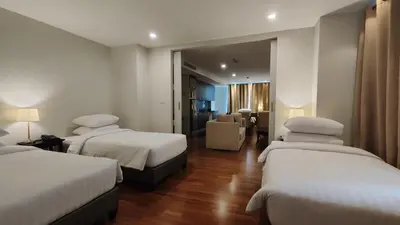 a hotel room with three beds and a living room at The Bless Hotel and Residence in Bangkok