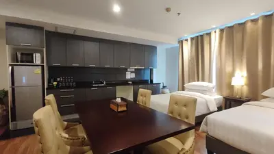a room with two beds and a dining room with a table at The Bless Hotel and Residence in Bangkok