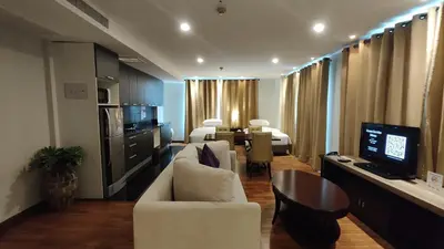 a living room with a white couch and a television at The Bless Hotel and Residence in Bangkok