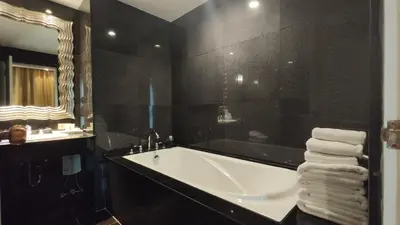 a black bathroom with a tub and a mirror at The Bless Hotel and Residence in Bangkok