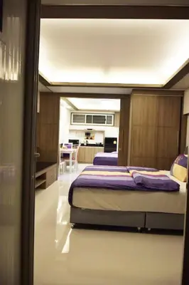 a bedroom with two beds with purple sheets and a kitchen at Family Suite Room Pratunam in Bangkok