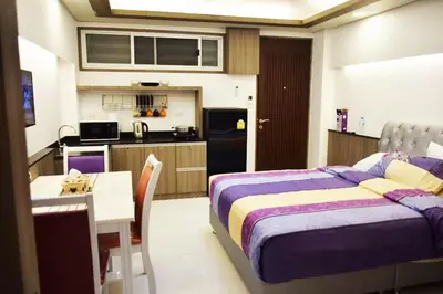 a bedroom with a bed and a table and a kitchen at Family Suite Room Pratunam in Bangkok