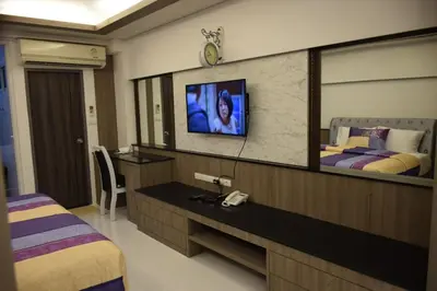 a hotel room with a tv and two beds at Family Suite Room Pratunam in Bangkok