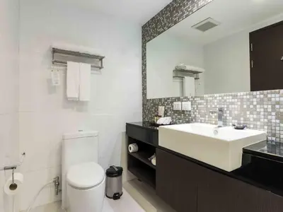 a bathroom with a sink and a toilet and a mirror at Maitria Hotel Sukhumvit 18 Bangkok – A Chatrium Collection in Bangkok