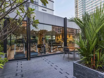 a glass building with a table and chairs in it at Maitria Hotel Sukhumvit 18 Bangkok – A Chatrium Collection in Bangkok