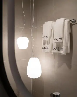 a bathroom with two lights and towels on a wall at Grand Inn Hotel in Bangkok