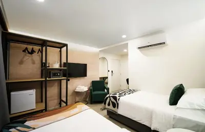 a hotel room with two beds and a television at Grand Inn Hotel in Bangkok