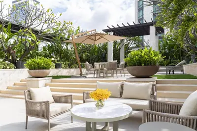 a patio with chairs and tables and an umbrella at Siam Kempinski Hotel Bangkok in Bangkok