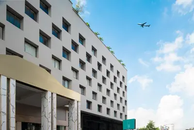 an airplane flies over the side of a hotel at Cross Vibe Bangkok Srinakarin in Bangkok