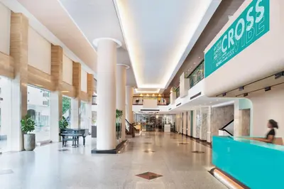 a lobby of a building with a woman sitting at a counter at Cross Vibe Bangkok Srinakarin in Bangkok