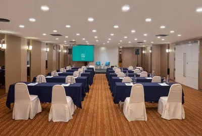 a conference room with tables and chairs and a screen at Cross Vibe Bangkok Srinakarin in Bangkok