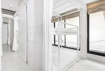 a bedroom with white walls and a ladder in front of a window at Nappark Hostel @Khao San in Bangkok