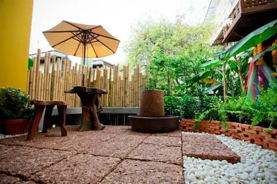 a patio with an umbrella and a table and bench at Nappark Hostel @Khao San in Bangkok