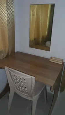 a wooden desk with a mirror and a chair at Little Home in Nonthaburi
