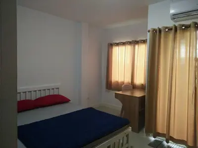 a bedroom with a bed and a desk and a window at Little Home in Nonthaburi